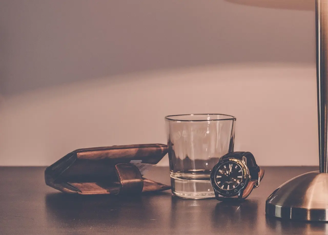 Natbord med lampe, glas, ur og små hverdagsting
